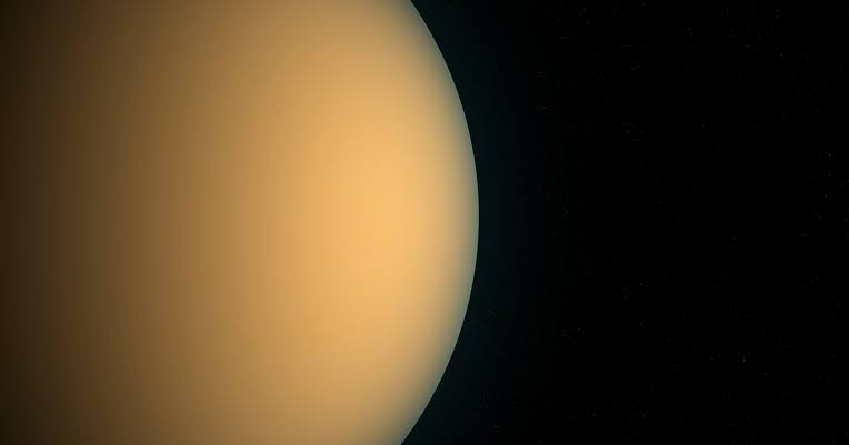 Titan turns so slowly that one rotation takes almost sixteen Earth days, and it is locked in place, showing Saturn the same face forever — so from one side of the moon the ringed planet hangs permanently in the sky, and from the other it is never seen at all